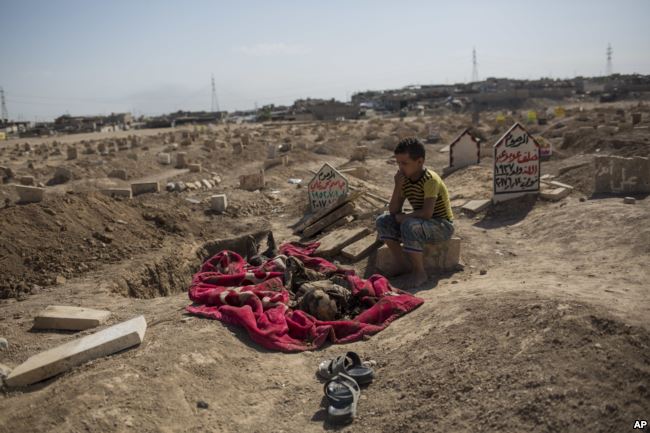 محمد محمود ثمانية أعوام يجلس قرب جثمان عمه في الموصل