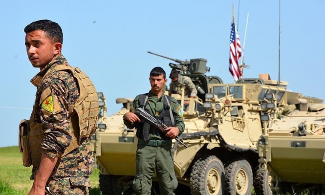 عنصران من الوحدات الكوردية مع آلية غسكرية أمريكية