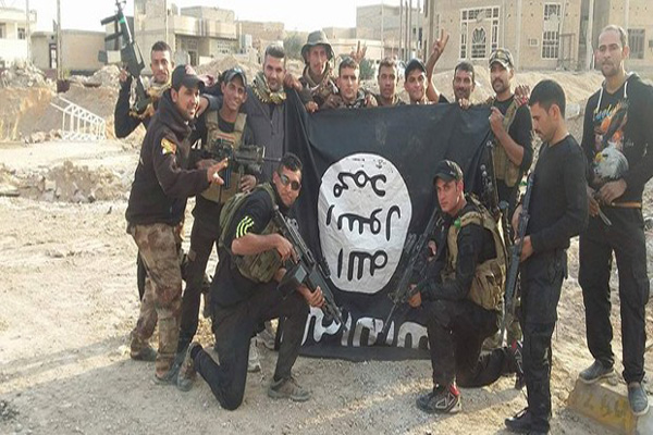 القوات العراقية تحمل راية داعش بالمقلوب