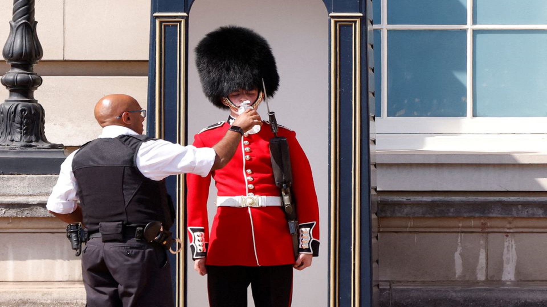 A member of the Queen's Guard receives water to drink during the hot weather, outside Buckingham Palace in London, Britain, July 18, 2022. REUTERS/John Sibley