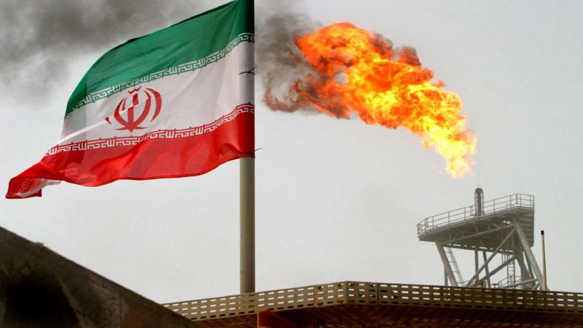 A gas flare on an oil production platform is seen alongside an Iranian flag. (Reuters)