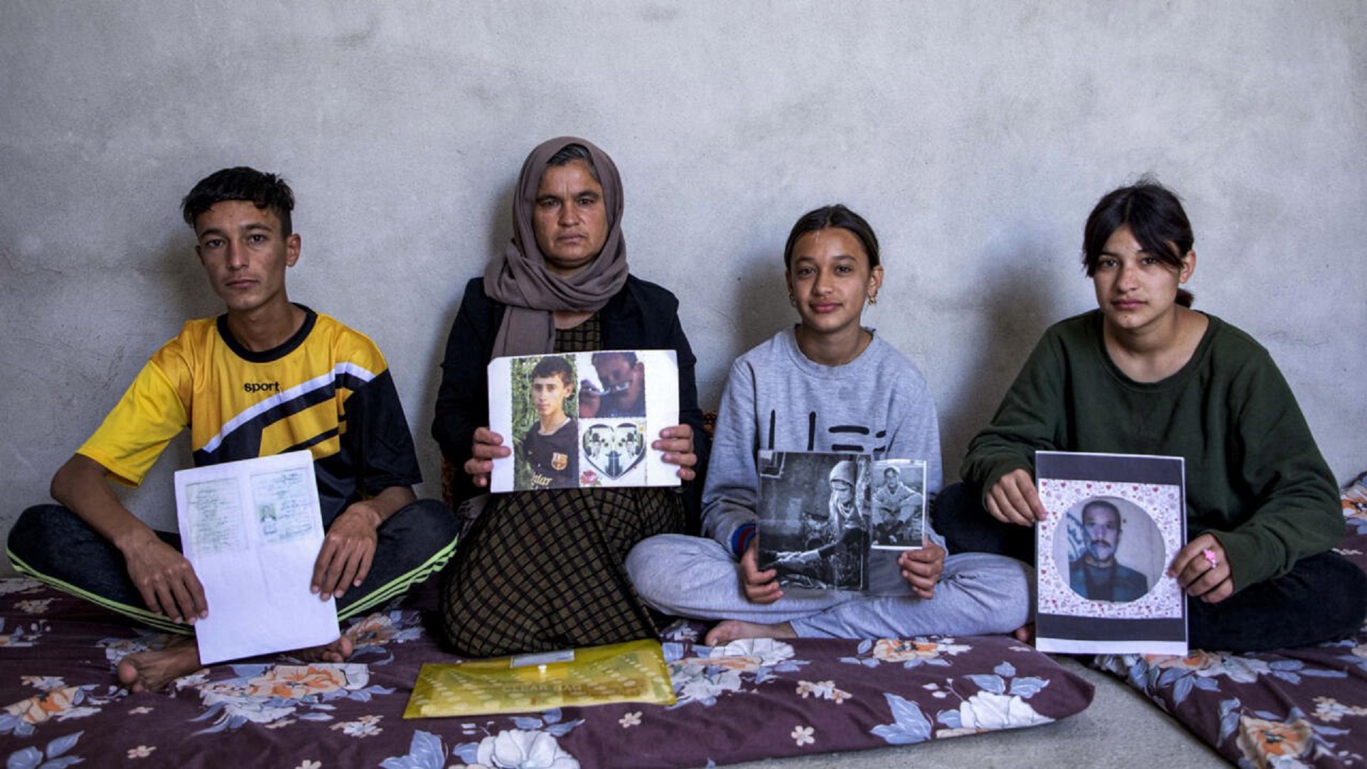 Four Yazidis with photographs of their family members