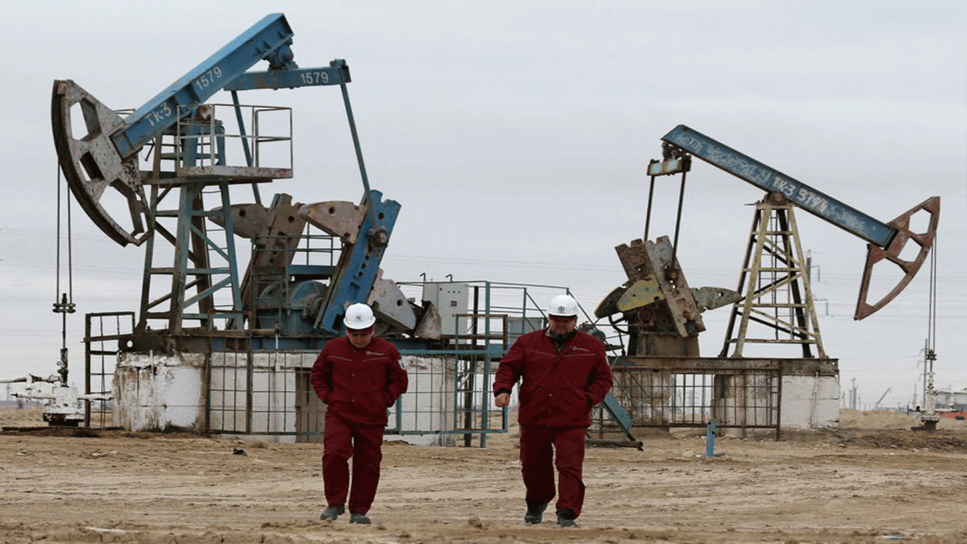 Workers walk as oil pumps are seen in the background in the Uzen oil and gas field in the Mangistau Region of Kazakhstan November 13, 2021. REUTERS/Pavel Mikheyev