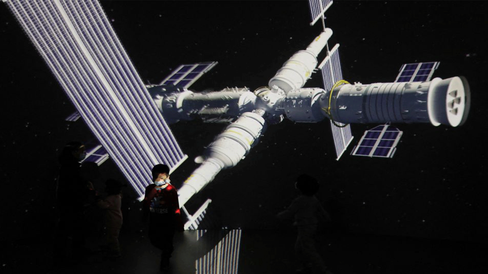  A child stands near a giant screen showing the image of the Tianhe space station on the country's Space Day at China Science and Technology Museum in Beijing, China April 24, 2021. REUTERS/Tingshu Wang/File Photo
